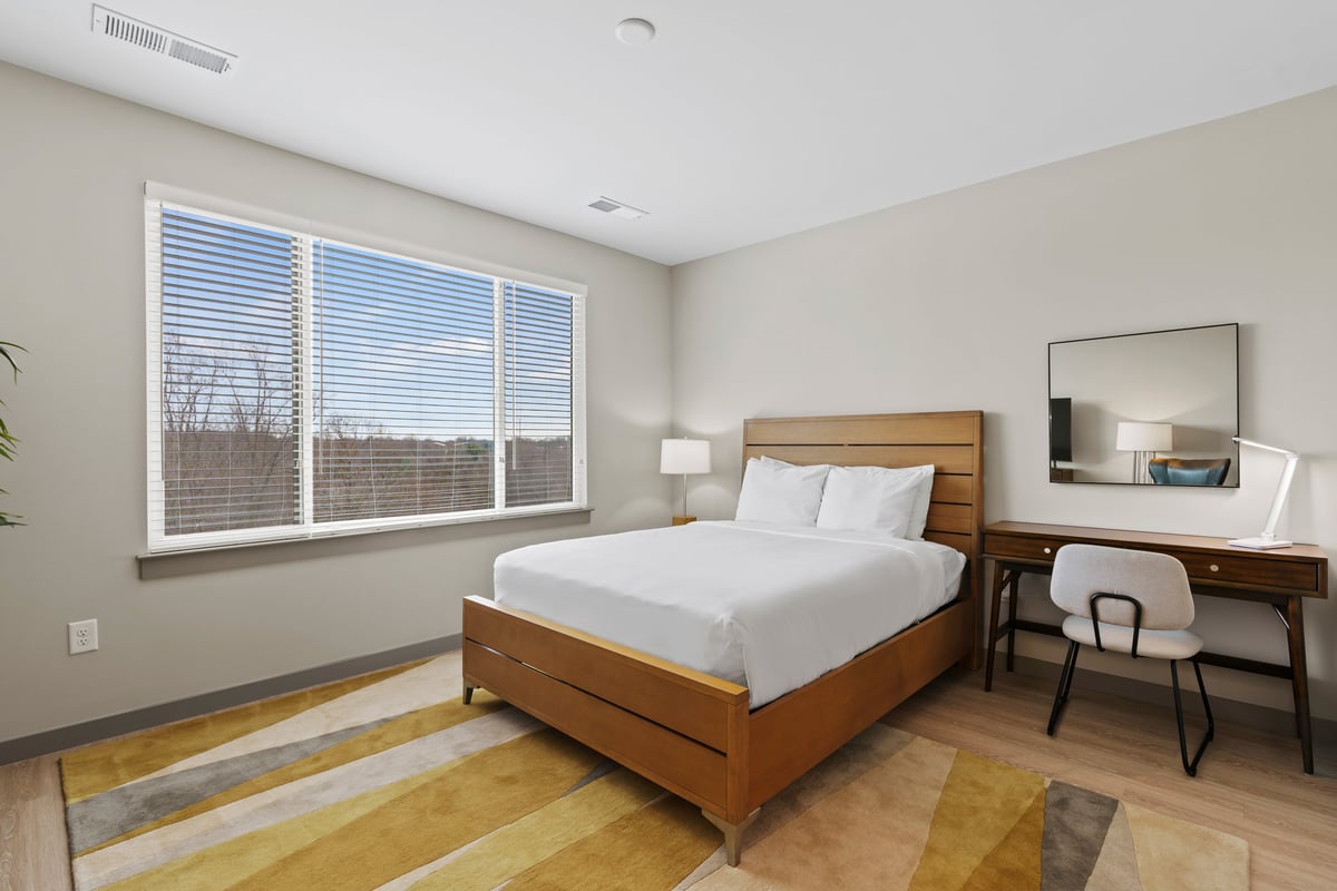 Queen bed and workspace in bedroom.